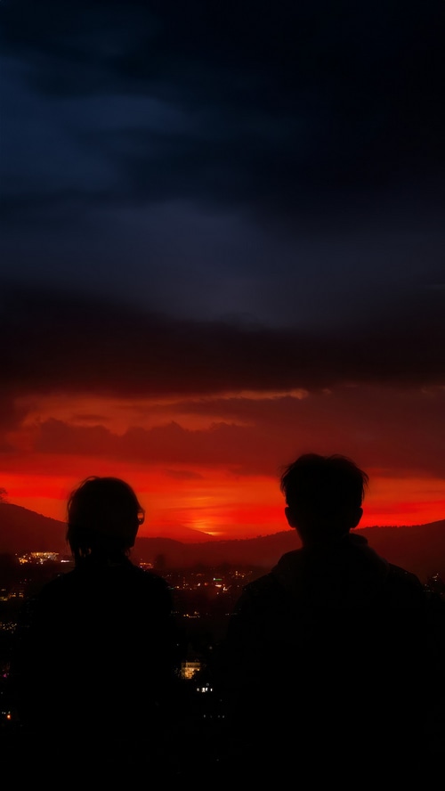 Couple watching a vibrant sunset over a city