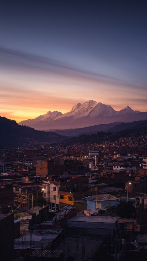 Cityscape at sunset with snow-capped mountains