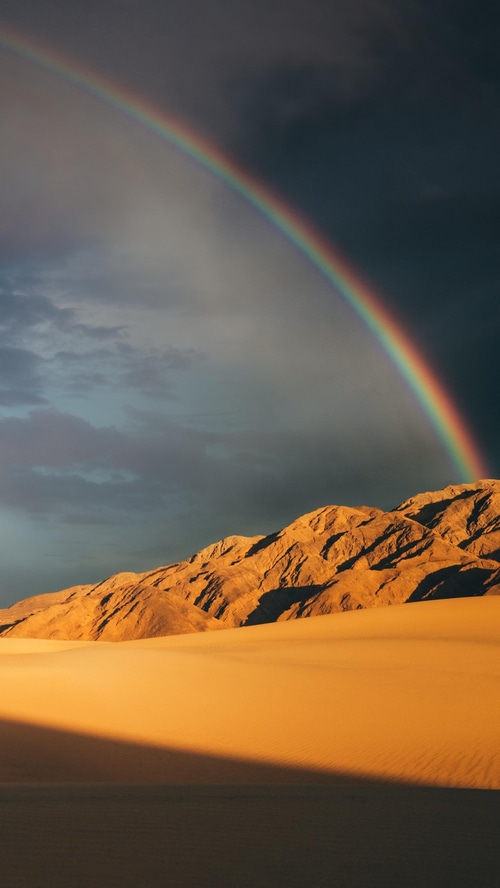 Rainbow over desert mountains and sand dunes