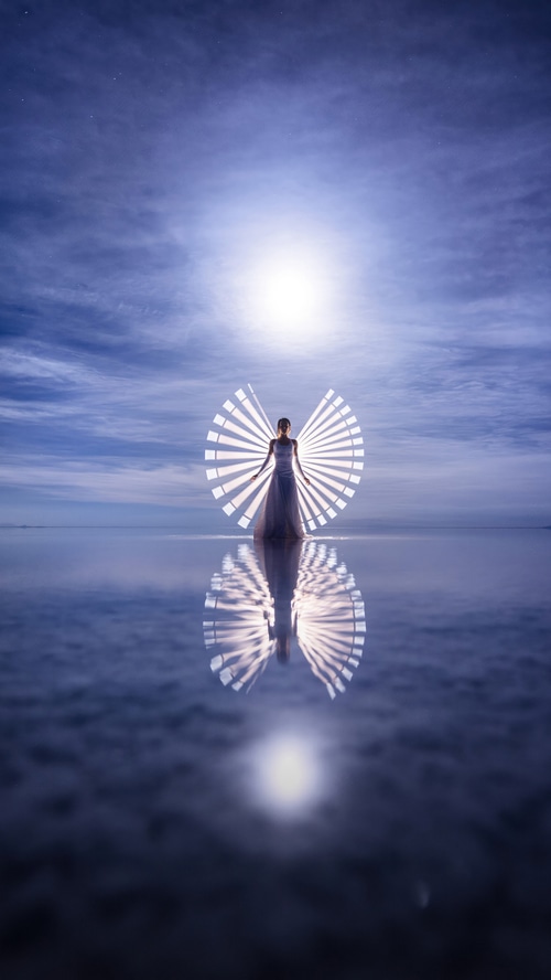 Woman with light wings reflected on water