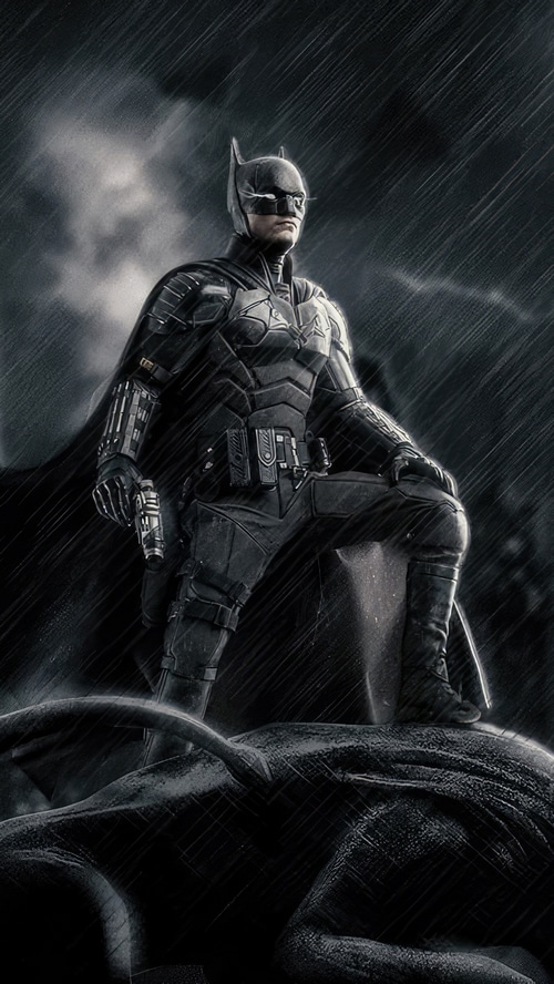 Batman standing on a defeated figure in the rain