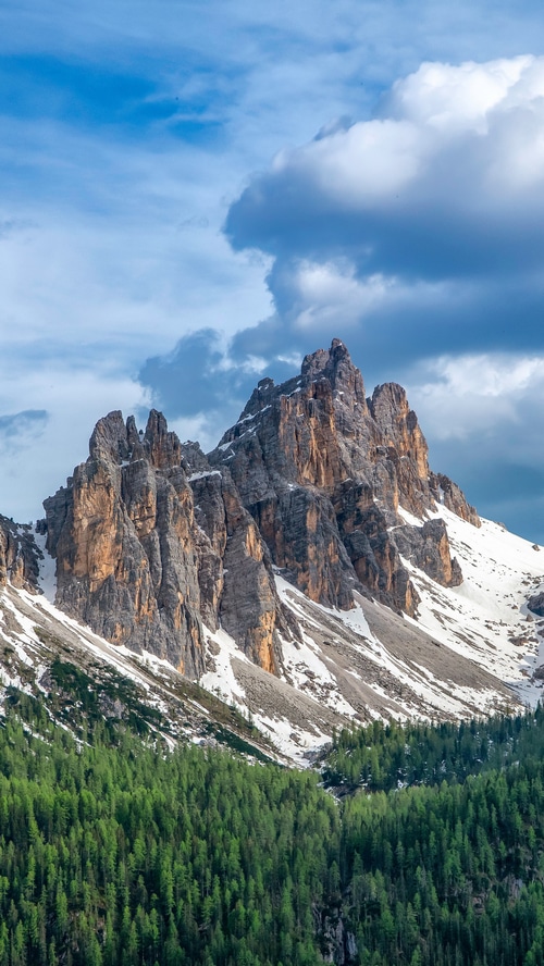 Rocky mountains in Italy with green forest and clouds