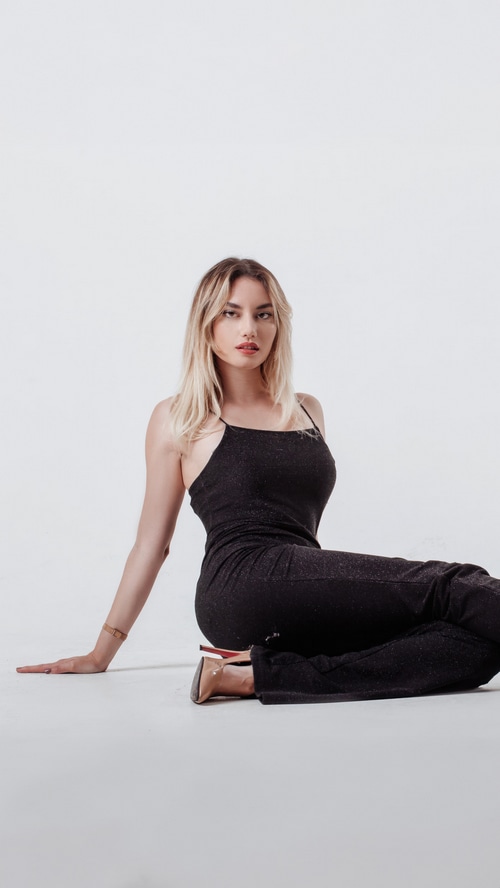 Model in a black dress sitting on a white background