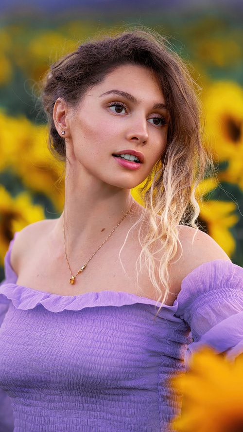 Model in a sunflower field wearing a purple dress