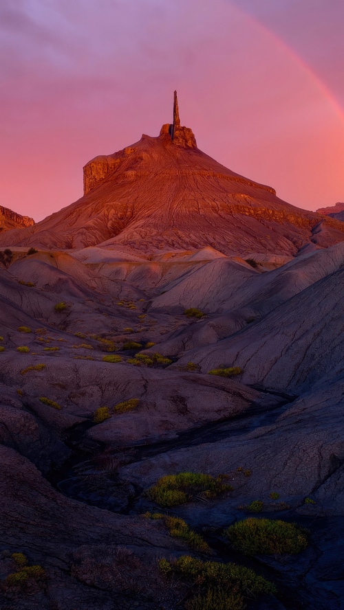 Desert landscape with rock formations and rainbow at sunset