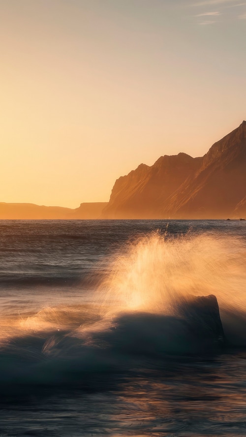 Ocean waves crashing on rocks at sunrise