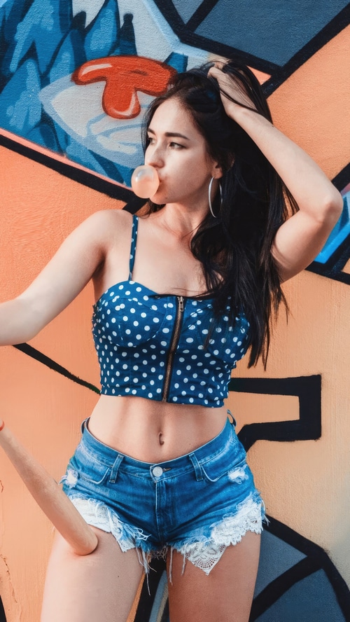 Model blowing bubblegum in front of graffiti