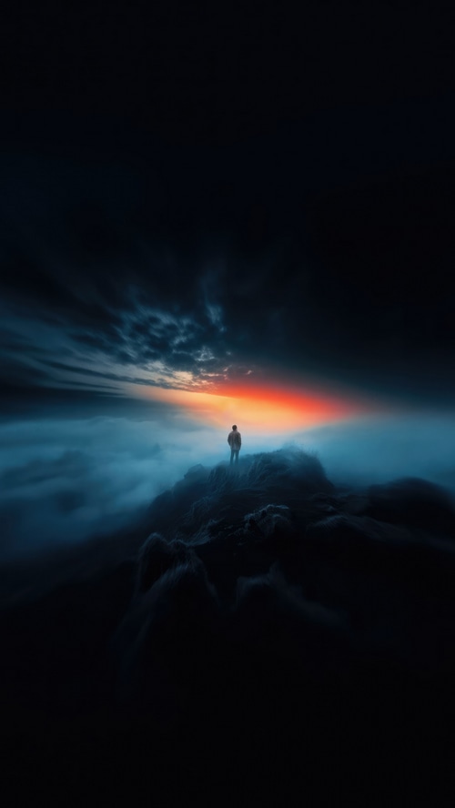 Man standing on a rocky outcrop in the clouds at sunset