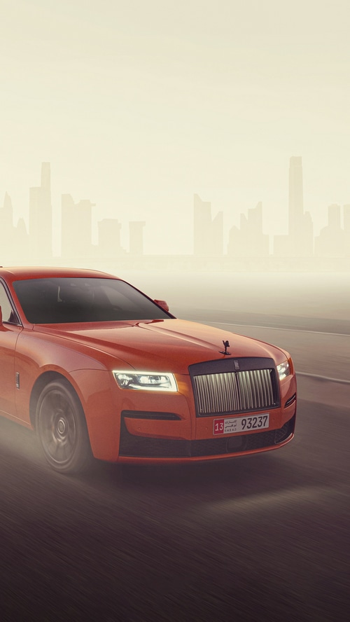 Orange Rolls-Royce Ghost driving in a hazy city