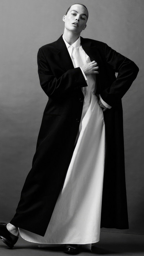 Margot Robbie in a black coat and white dress