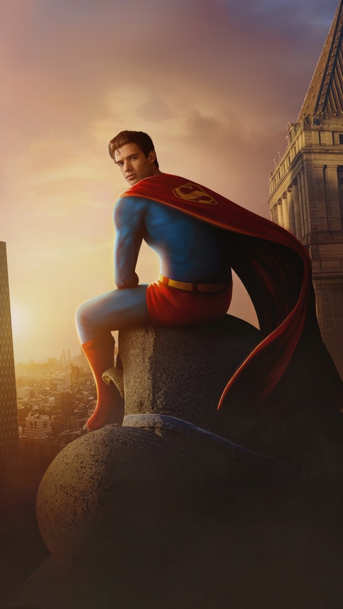 Superman sitting on a building overlooking a city at sunset