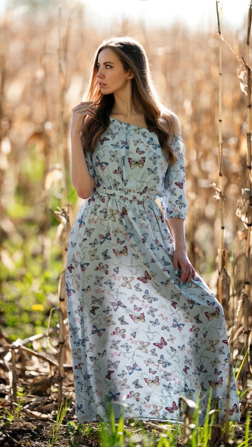 Woman in a butterfly print dress in a field