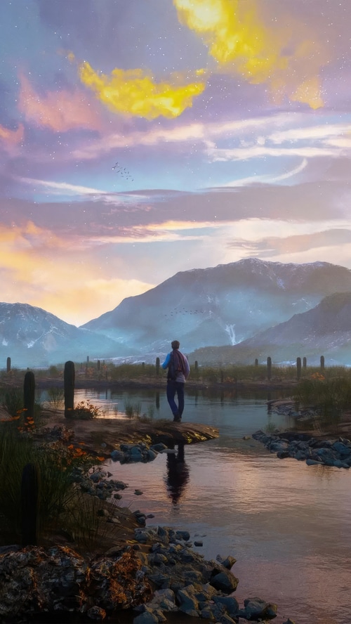 Man with backpack by a lake with mountains