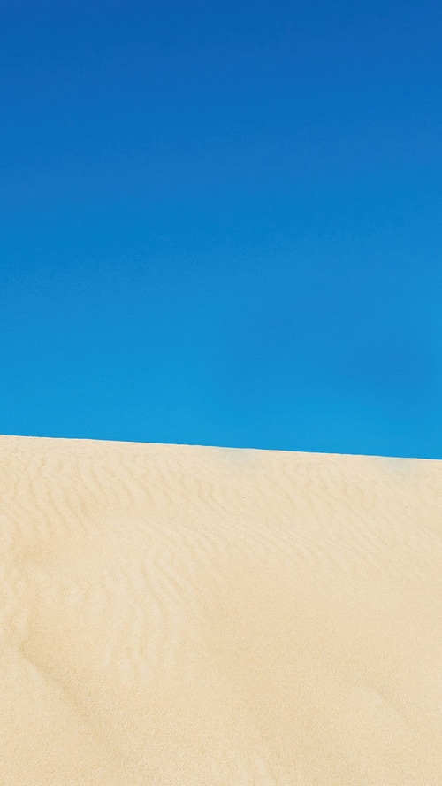 Desert sand dunes under a clear blue sky
