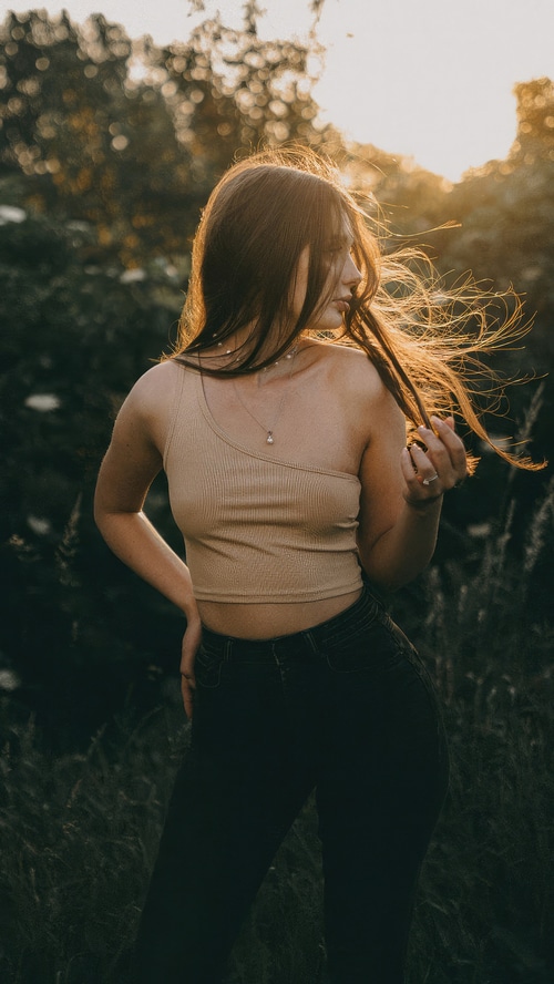 Model with long hair in a tan top and black jeans