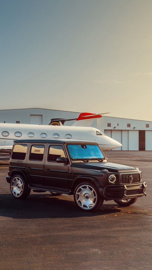 Mercedes G-Class parked by a private jet