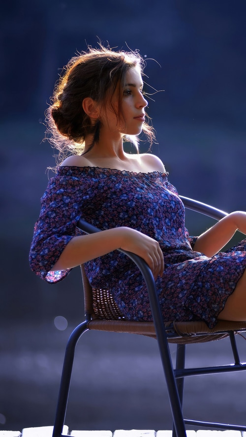 Young woman in a floral dress sitting on a chair