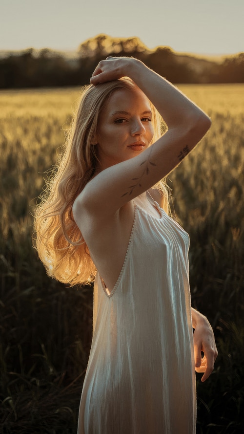Woman in white dress in a field at sunset