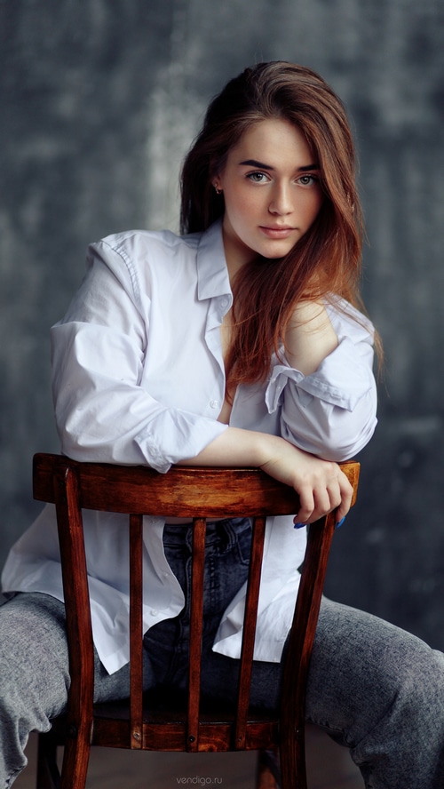 Model in a white shirt and jeans sitting on a chair