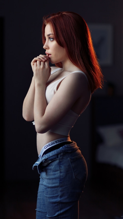 Model with red hair wearing jeans and white top