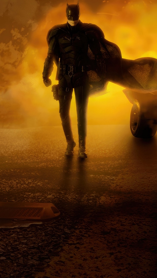 The Batman standing in front of a fiery orange sky
