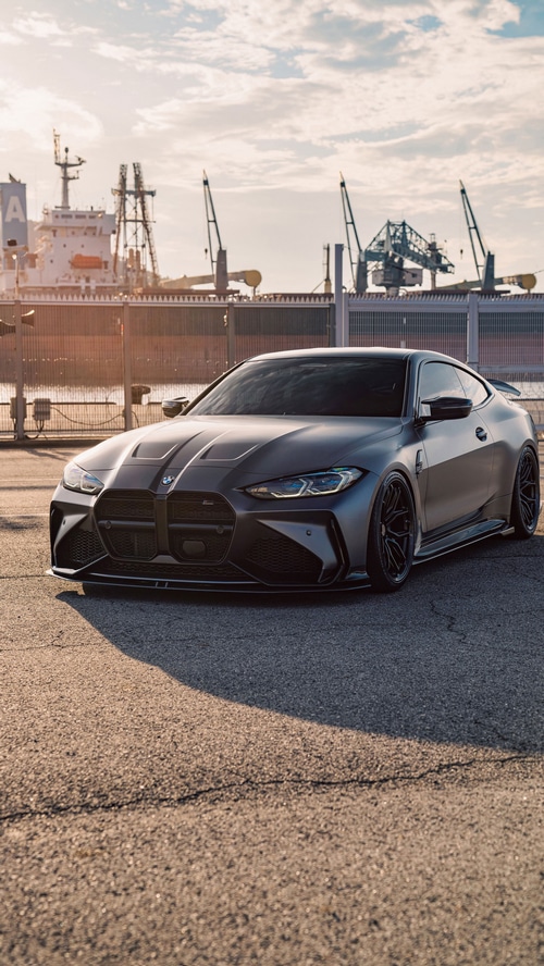 Matte gray BMW M4 coupe parked by a harbor
