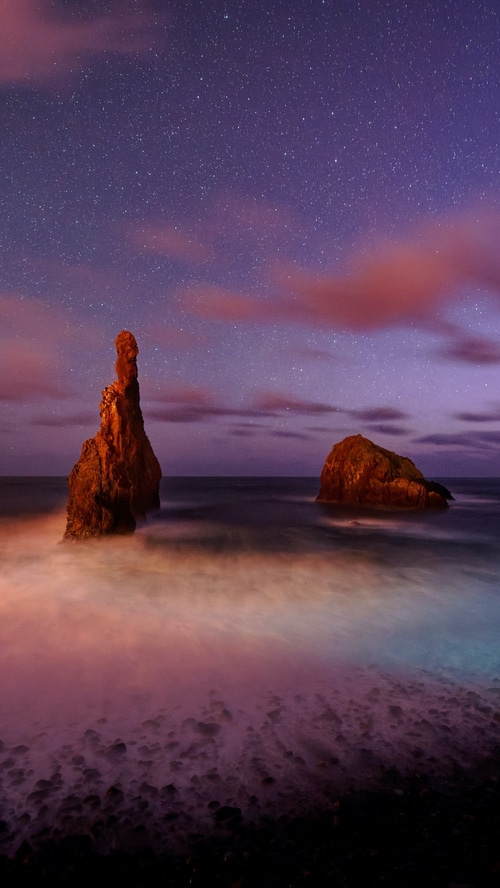 Sea stacks under a starry sky at dusk
