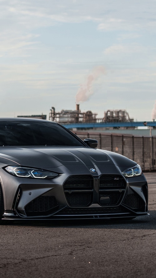 BMW M4 parked in front of industrial background
