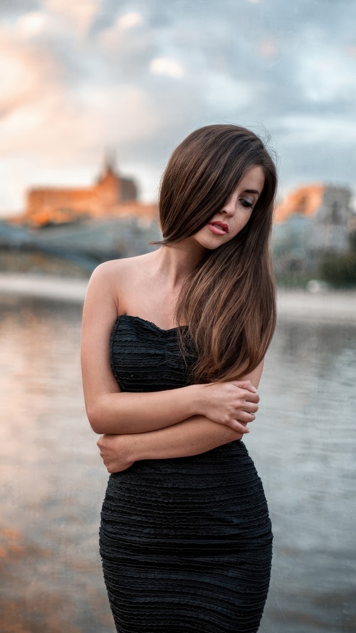 Woman in a black dress by the water