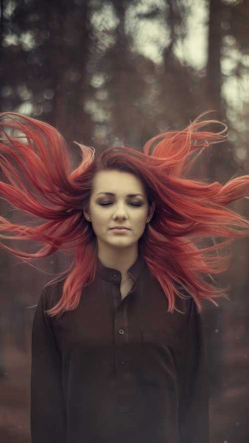 Woman with flowing red hair in a dark shirt