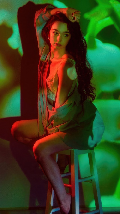 Ruby Jay posing in a studio with colored lights
