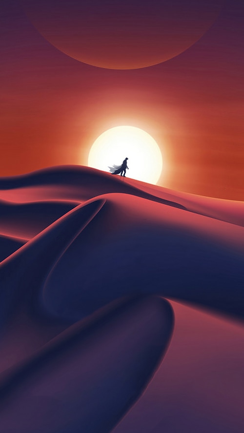Man walking on sand dunes during sunset