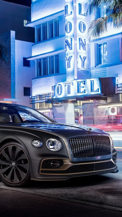 Bentley Flying Spur parked in front of a hotel at night