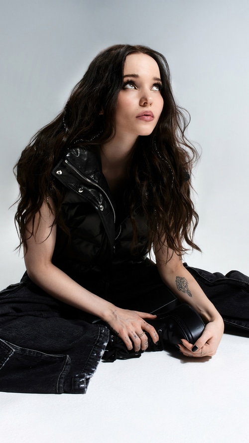 Dove Cameron sitting on the floor in black outfit
