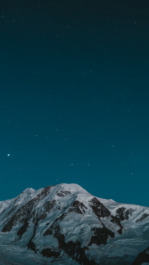 Snow-covered mountains under a starry night sky
