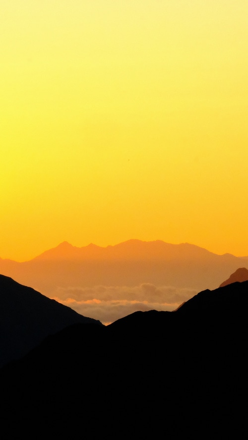 Silhouette of mountains against a yellow sky
