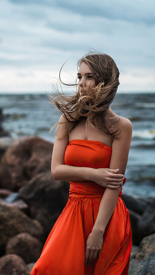 Woman in orange dress on rocky shore