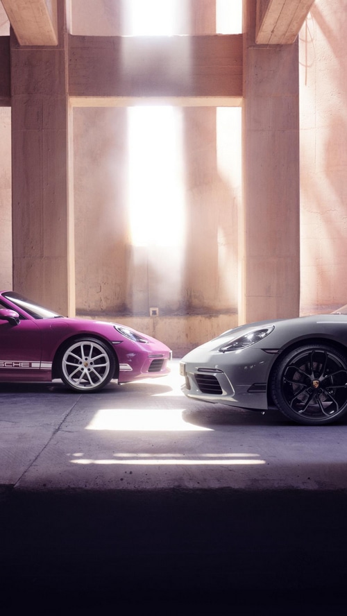 Two Porsche cars parked in a sunlit architectural space