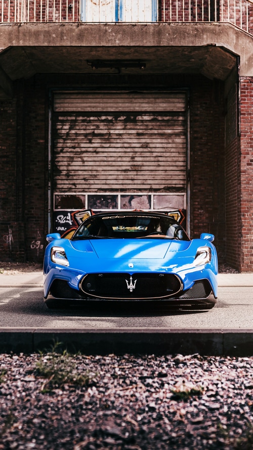 Blue Maserati MC20 parked in front of a garage
