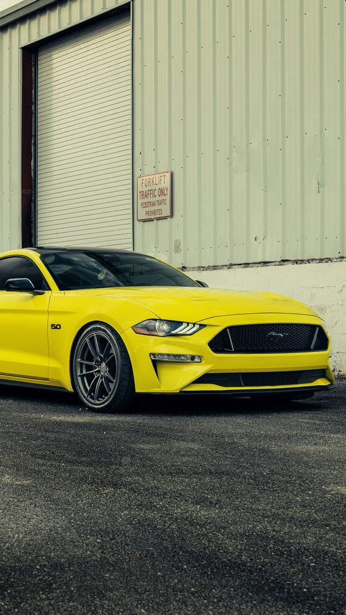 Yellow Ford Mustang 5.0 parked outside a building