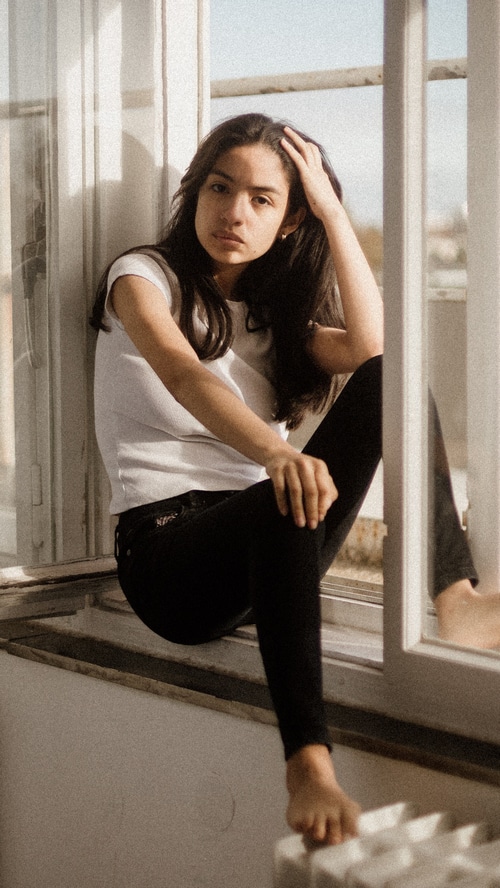 Young woman sitting on a windowsill
