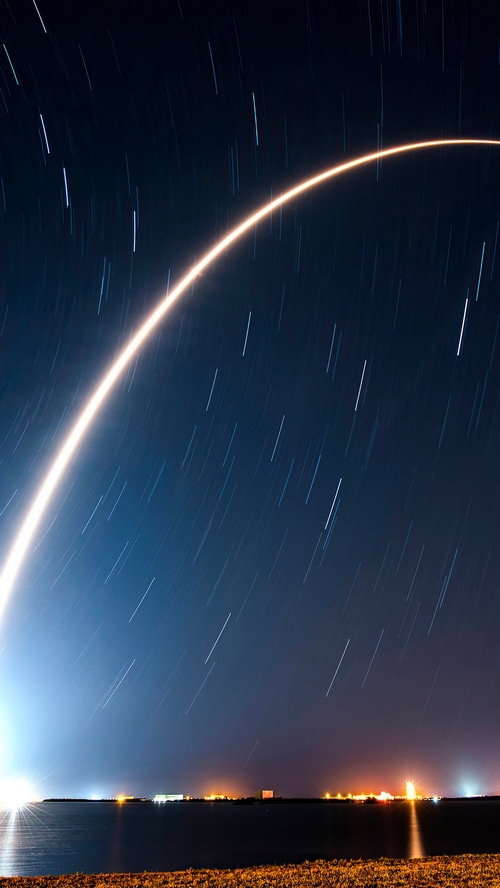SpaceX Rocket Launch Trail Over Water at Night