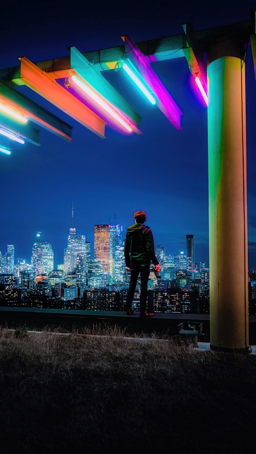 Man on rooftop overlooking city skyline at night