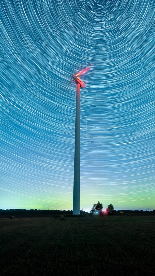Windmill under star trails with aurora
