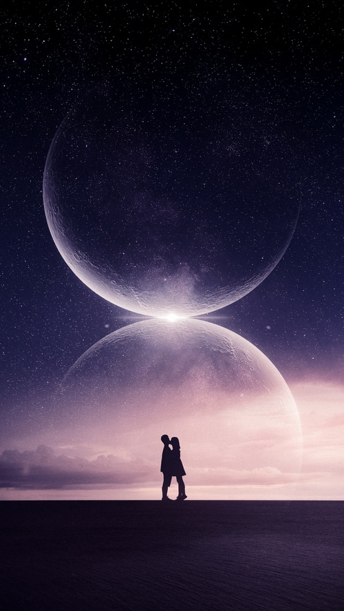 Couple silhouetted against two large moons in space