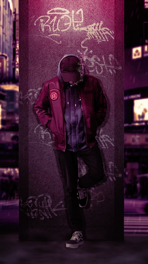 Man leaning against graffiti-covered pillar in city