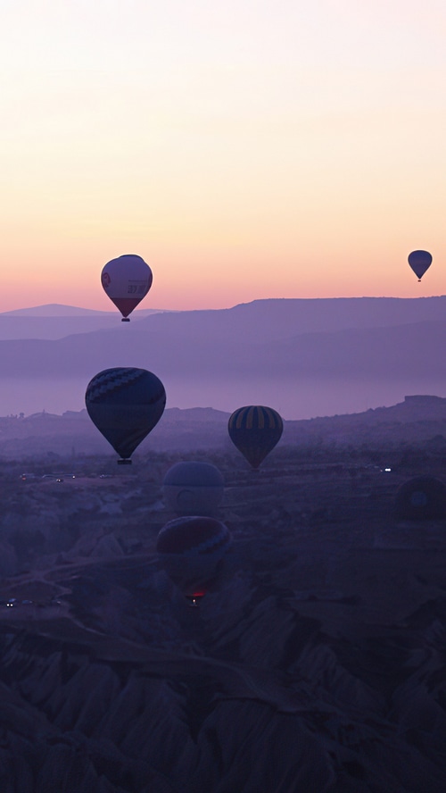 Hot air balloons at sunset over a mountainous landscape