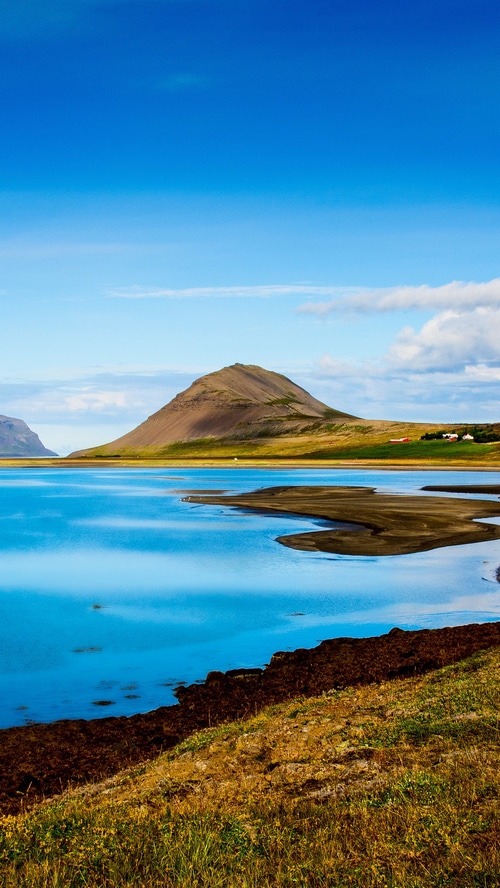 Icelandic landscape with a conical mountain and blue water