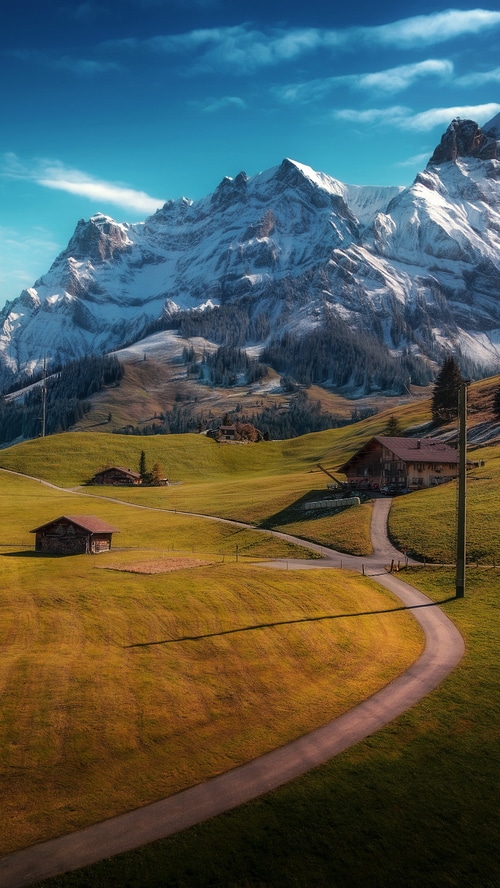 Snow-capped mountains and green hills with houses