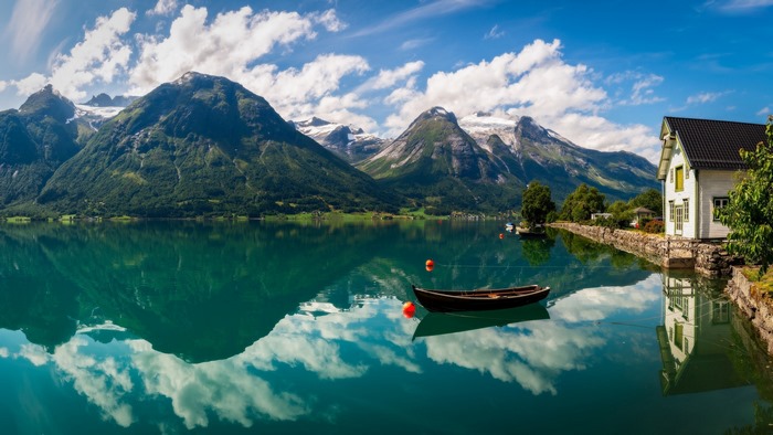 Boat on a lake with mountains and a house